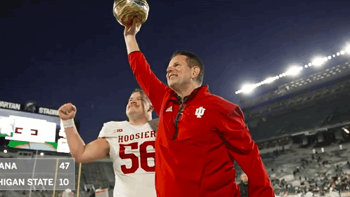 A Man In A Hoosier 56 Jersey Holds Up A Football GIF