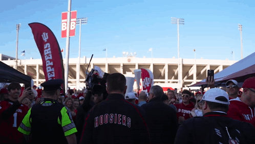 A Man In A Hoosier 'S Jacket Stands In Front Of A Crowd GIF