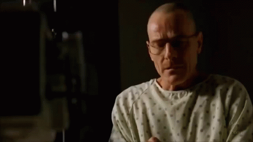 a man in a hospital gown is crying while sitting on a bed .