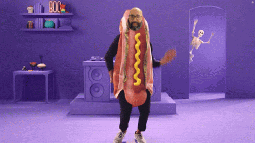A Man In A Hot Dog Costume Is Dancing In A Purple Room GIF