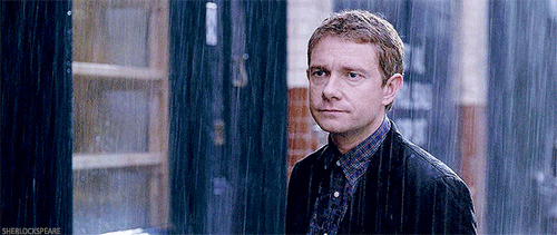 A Man In A Jacket Is Standing In The Rain Looking At The Camera . GIF