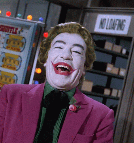 A Man In A Joker Costume Is Laughing In Front Of A No Loafing Sign GIF