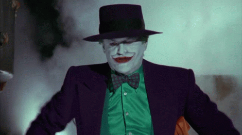 A Man In A Joker Costume Is Wearing A Green Shirt And A Purple Hat GIF