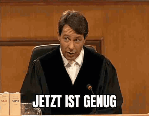 A Man In A Judge 'S Robe Is Sitting In Front Of A Microphone And Says Jetzt Ist Genug GIF