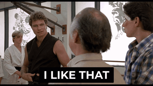 A Man In A Karate Uniform Is Talking To Two Other Men With A Sign That Says I Like That GIF