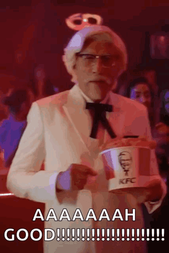 A Man In A Kfc Costume Is Holding A Bucket Of Fried Chicken GIF