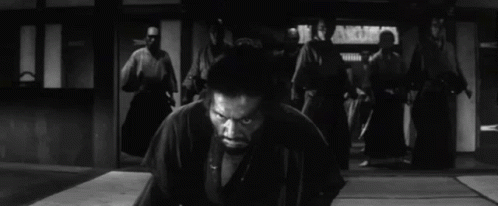 A Man In A Kimono Is Kneeling Down In Front Of A Group Of Samurai . GIF