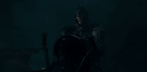 a man in a knight 's armor is riding a horse in the dark .