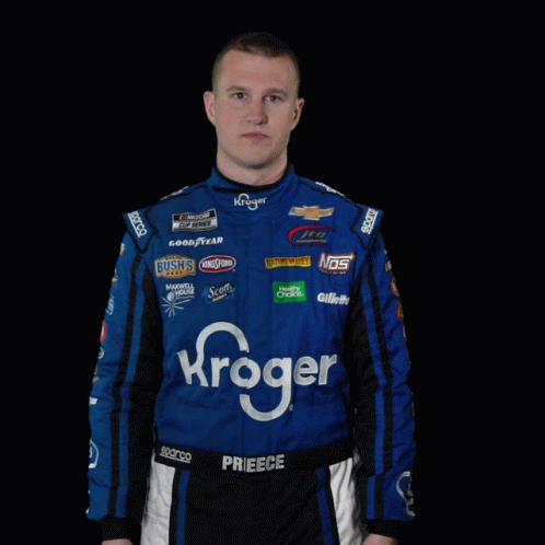 a man in a kroger racing suit is standing with his hands outstretched