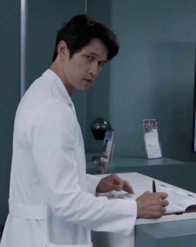 A Man In A Lab Coat Is Standing In Front Of A Counter GIF