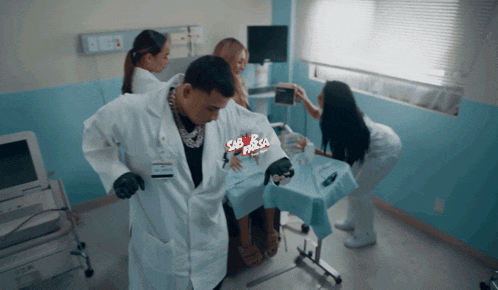 A Man In A Lab Coat Is Standing Next To A Woman In A Hospital Bed With A Sign That Says Sabrosa GIF