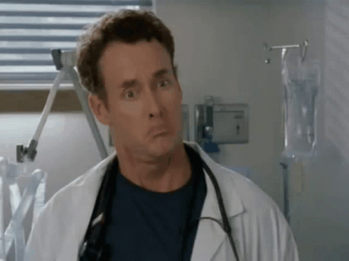A Man In A Lab Coat With A Stethoscope Around His Neck Is Making A Funny Face In A Hospital Room . GIF