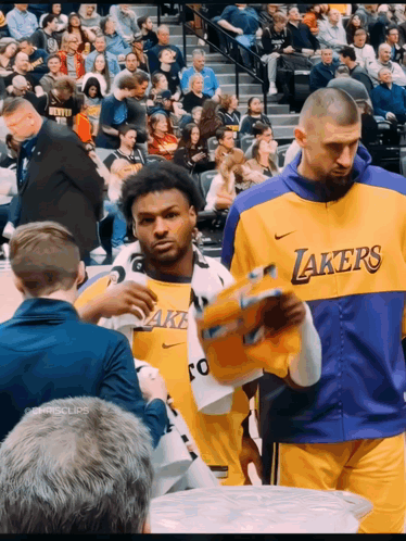 a man in a lakers jersey holds a basketball in his hand