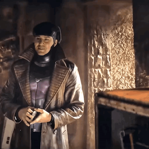 A Man In A Leather Coat And Helmet Is Standing In A Room GIF