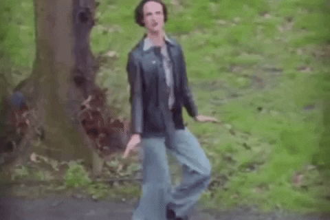 A Man In A Leather Jacket And Blue Jeans Is Dancing In The Woods . GIF