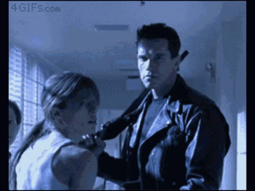 A Man In A Leather Jacket Holds A Gun To A Woman 'S Neck And Says 4Gifs.com At The Bottom GIF