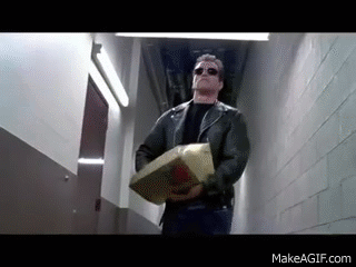 A Man In A Leather Jacket Is Carrying A Box Down A Hallway . GIF