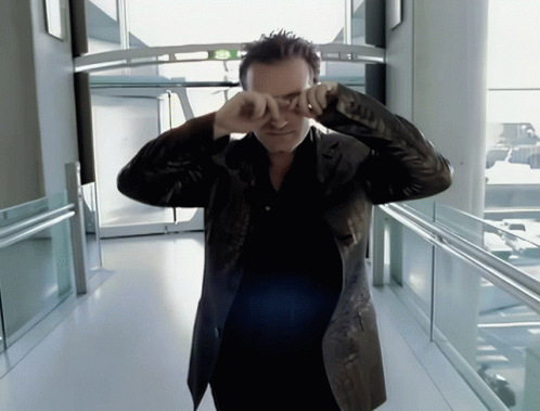 a man in a leather jacket is covering his eyes with his hands