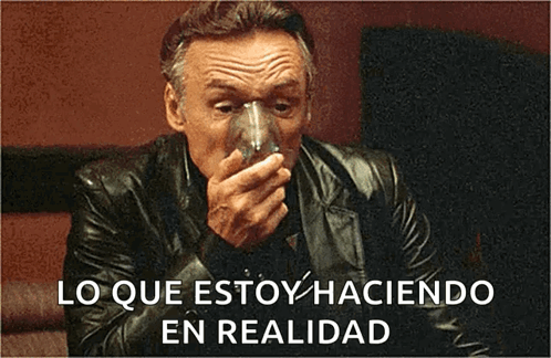 A Man In A Leather Jacket Is Drinking From A Glass With The Words " Lo Que Estoy Haciendo En Realidad " Below Him GIF