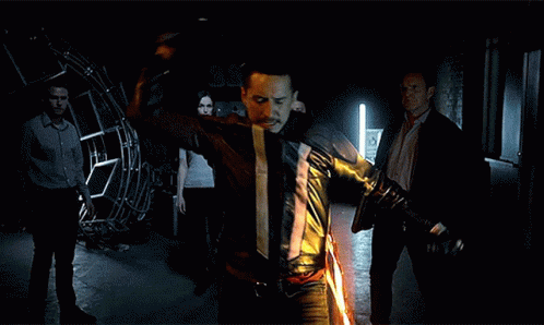 A Man In A Leather Jacket Is Holding A Flaming Sword GIF