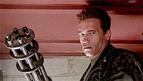 A Man In A Leather Jacket Is Holding A Gun GIF