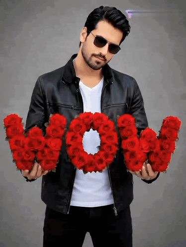 A Man In A Leather Jacket Is Holding A Wreath Of Red Roses That Spell Out The Word Wow GIF