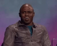 a man in a leather jacket is making a funny face while sitting in front of a purple background .