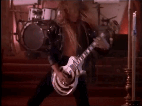 A Man In A Leather Jacket Is Playing A Guitar In A Church . GIF
