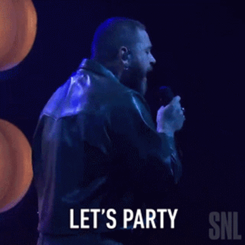 A Man In A Leather Jacket Is Singing Into A Microphone And Says Let 'S Party Snl GIF