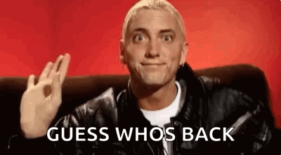 A Man In A Leather Jacket Is Sitting On A Couch Giving An Okay Sign . GIF