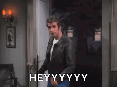 A Man In A Leather Jacket Is Standing In A Doorway And Says Hey . GIF