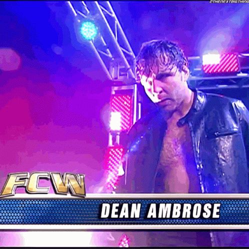 A Man In A Leather Jacket Is Standing In Front Of A Banner That Says Fcw Dean Ambrose GIF