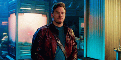 A Man In A Leather Jacket Is Standing In Front Of A Building . GIF