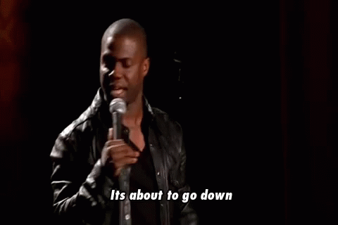 A Man In A Leather Jacket Is Standing In Front Of A Microphone And Talking Into It . GIF