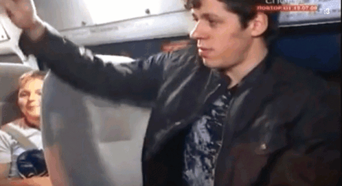 A Man In A Leather Jacket Is Standing In Front Of A Screen That Says " Rostov " On It GIF