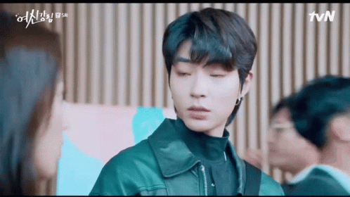 A Man In A Leather Jacket Is Standing In Front Of A Woman In A Room . GIF