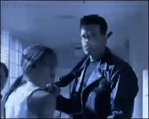 A Man In A Leather Jacket Is Talking To A Woman In A White Tank Top GIF