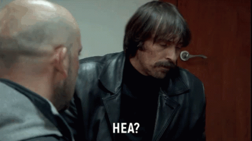 A Man In A Leather Jacket Says Hea While Talking To Another Man GIF