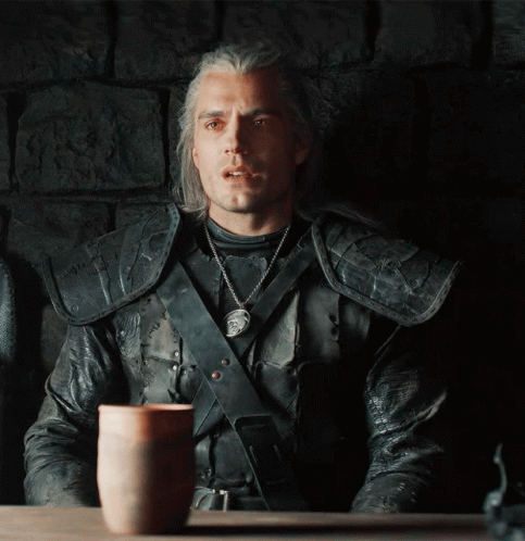 A Man In A Leather Jacket Sits At A Table With A Cup On It GIF