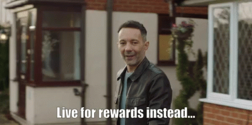 A Man In A Leather Jacket Stands In Front Of A House With The Words Live For Rewards Instead Written Below Him GIF