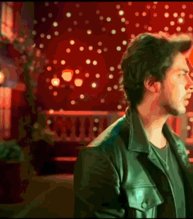 A Man In A Leather Jacket Stands In Front Of A Red Background GIF
