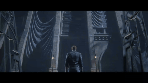 a man in a leather jacket stands in front of a very tall building