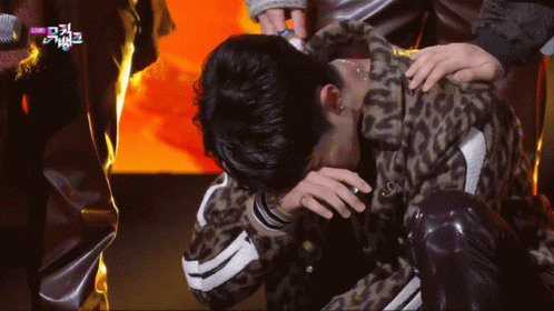 A Man In A Leopard Print Jacket Is Kneeling Down With His Head In His Hands GIF
