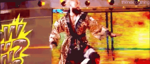 a man in a leopard print robe is standing on a stage in front of a large screen .