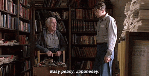 A Man In A Library Talking To An Older Man Who Is Carrying A Basket Full Of Books . GIF