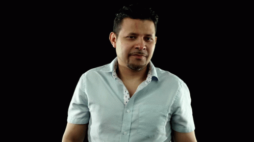 A Man In A Light Blue Shirt Is Making A Gesture With His Hands GIF