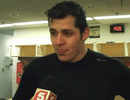A Man In A Locker Room With A Penguins Sign On The Wall GIF