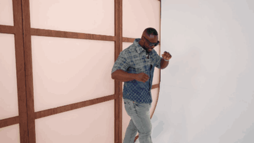 A Man In A Louis Vuitton Shirt Is Standing In Front Of A Wooden Wall GIF