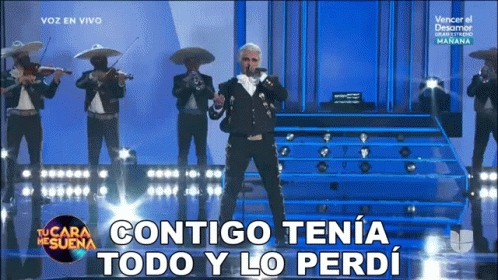 a man in a mariachi outfit sings into a microphone with the words contigo tena todo y lo perdi below him