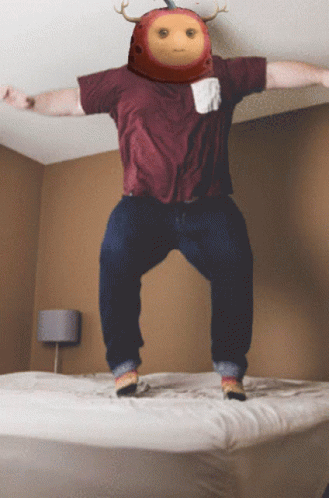 A Man In A Maroon Shirt Jumps On A Bed GIF